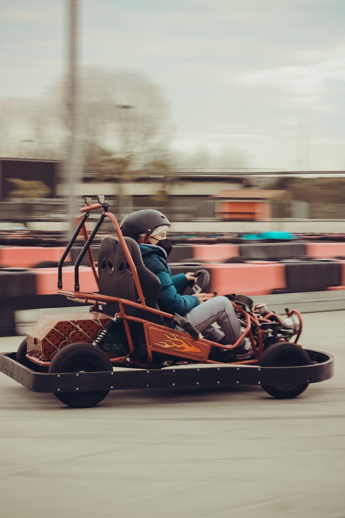 A teenager in a helmet driving a go-kart on an outdoor speedway, capturing the thrill and motion.